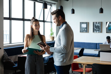 Caucasian businessman explaining strategy to colleague over digital tablet in office