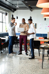 Surprised african american businessman with laptop by colleagues in office