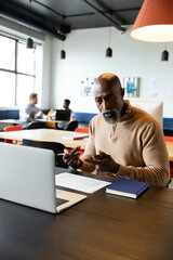 Obraz na płótnie Canvas African american mature businessman video calling through laptop in creative office