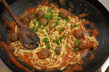 Homemade tagliatelle with sauce and meatballs cooked on a disc