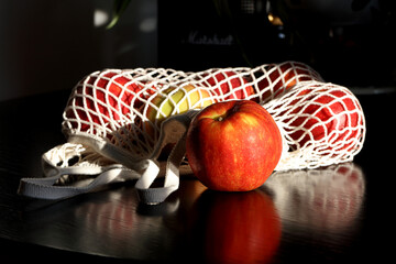 Ripe red apples in a knitted string bag