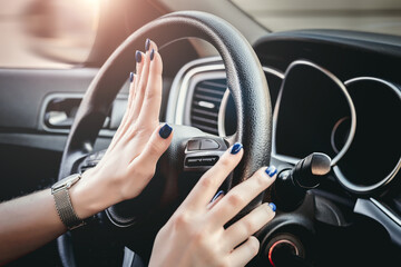 Woman pressing honk button on steering wheel. Female hand honking while driving a car.
