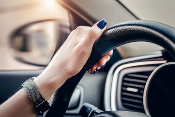 female hand is holding the steering wheel of a car. close up. Traveling alone. Traffic Laws. Learns to drive a car. woman driver