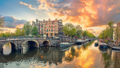 Naklejka premium Amsterdam. Panoramic view of the downtown of Amsterdam. Traditional houses and bridges of Amsterdam. A colorful sundown time. Vintage toned.