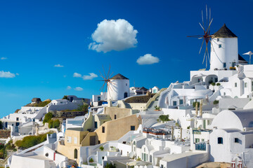 Windmills and cityscape of Oia town on Santorini island in Greece. Traditional white houses....
