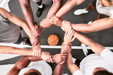 Fototapeta na wymiar Athletes showing trust and standing united. Men expressing team spirit with their hands joined huddling at a basketball game. Sportsmen holding wrists in huddle for support and unity at sports match.