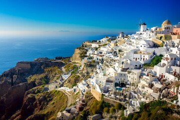 Fototapeta na wymiar Famous Santorini, Greece. Charming view of the village of Oia on the island of Santorini. Traditional famous windmills with and white houses above the caldera in the Aegean.