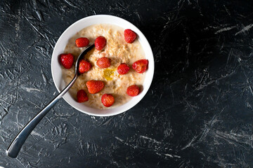 A bowl of oatmeal with butter and strawberries