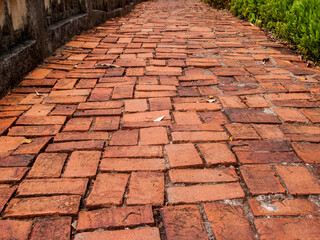 The walkway is paved with ancient red bricks.