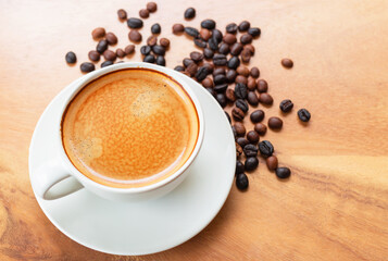 Close-up of a cup of latte with golden foam and mixed or blend coffee beans in a brown sack on an old wooden floor, top view.