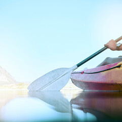 Closeup of kayak oar paddle rowing on calm water. Female hands kayaking on a lake during summer...