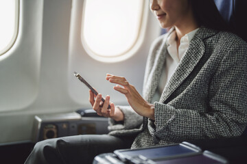 A successful asian businesswoman or female entrepreneur in formal suit in a plane sits in a...