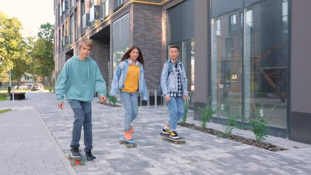 Caucasian cheerful young teenagers riding on skateboards having fun. Boys and girl friends outdoors spending time together in city. Urban style, leisure activity, skateboarding, skaters on boards