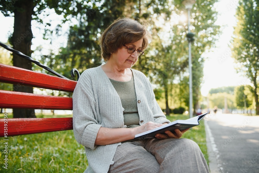 Poster Retired woman reading a book on the bench