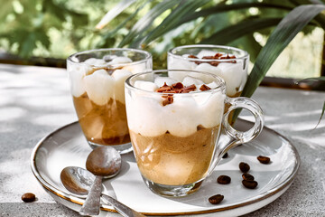 Traditional Italian dessert Tiramisu in glass cups on gray table. National cuisine recipe. Summer refresh coffee cream sweet mousse dish.