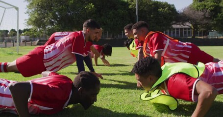 Video of diverse group of male football players warming up on field,doing push-ups - Powered by Adobe