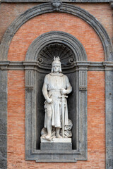 Fototapeta na wymiar Marble statue of medieval king decorating a niche in the exterior facade of a building in Napoli