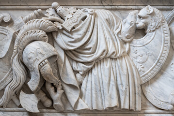 Close-up on ancient roman war objects and clothes carved in a decorated marble wall
