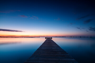 Horizontal photo of the sunrise and the calm waters of the Mar Menor, Region of Murcia, Spain, from a wooden jetty in San Javier