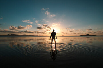 Silhouette of a man standing with his back facing at sunset over the shallow waters of the Mar...
