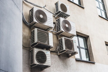 Multiple air conditioning units with fans on a office building exterior wall