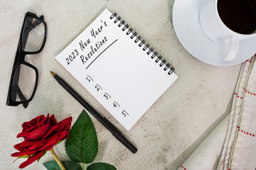 2023 New Year's Resolutions written on notebook on white marble table.