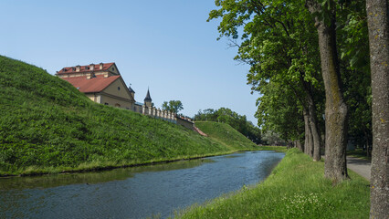 Naklejka premium Fortress moat with water reflecting trees and castle walls. Bridge over the moat.