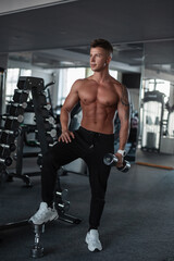 Fototapeta na wymiar Sporty muscular male fitness trainer bodybuilder with a muscular body working out in the gym