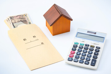 住宅ローン返済・不動産購入のイメージ（給料と家の模型と電卓）
