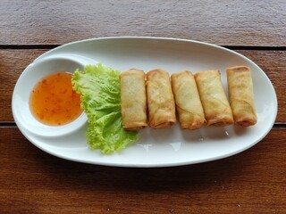 Fried Spring Roll served with vegetables salad and sweet dip in a white dish
