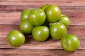 Green plum on wood background. Pile of green plums. close up