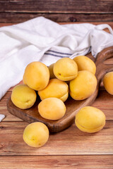 Apricots on wood background. Stack of fresh apricots in a wooden serving plate. close up