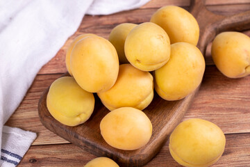 Naklejka na ściany i meble Apricots on wood background. Stack of fresh apricots in a wooden serving plate. close up
