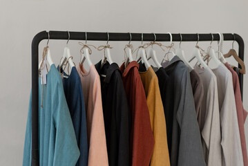 Minimalistic rack with linen colourful clothes on white studio background.