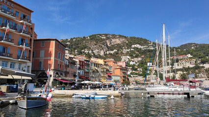 Villefranche-sur-Mer, France, October 2, 2021: View of Port Villefranche-Santé with boats, catamarans, sails boats, speed boats, and yachts moored to the pier, during daytime with a clear blue sky. - obrazy, fototapety, plakaty