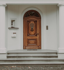 Beautiful wooden door with knocker, house entrance with white columns