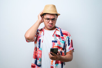 Portrait of unhappy Asian man in casual beach shirt holding mobile phone with sad expression on...