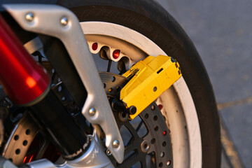 Close up view of the anti theft system placed on the front wheel of a motorcycle. - obrazy, fototapety, plakaty