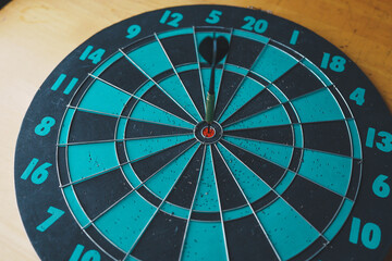 Close up shot of the dart arrow hit on bulleyes of dartboard to represent that the business reached the target of company with dark tone picture style. Target and goal as concept. 