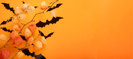 Orange Halloween background. Flock of black bats and branch of dry orange flowersfor Halloween....