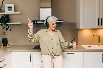 Smiling elderly woman dancing to her favourite music at home