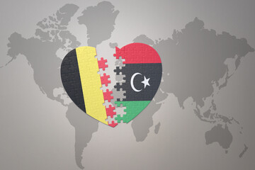 puzzle heart with the national flag of belgium and libya on a world map background.Concept.