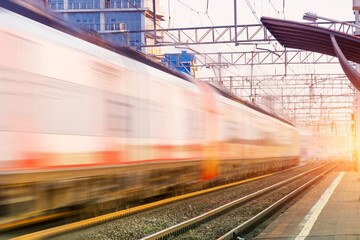 Railroad in motion at sunset. Railway station with motion blur effect against colorful blue sky....