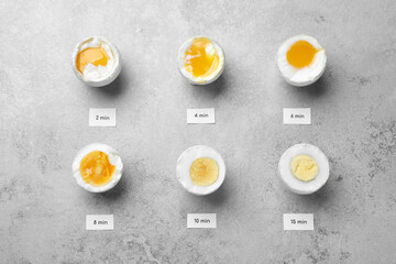 Different cooking time and readiness stages of boiled chicken eggs on light grey table, flat lay