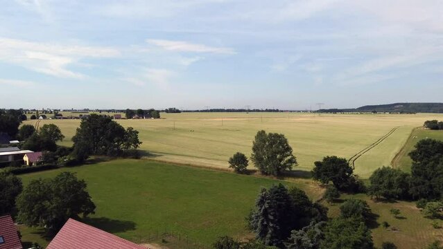 Blue sky, yellow field, green grass.
Stunning aerial view flight fly forwards drone footage
at Countryside village Hainichen in Europe Saxony Anhalt, summer. 4k Cinematic from above by Philipp Marnitz