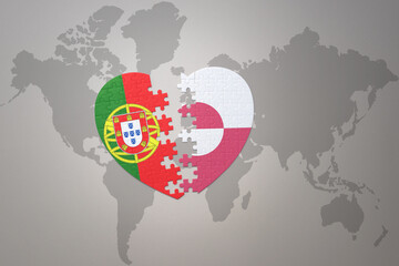 puzzle heart with the national flag of portugal and greenland on a world map background.Concept.