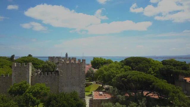 Aerial drone footage of the Lisbon medieval castle in the medieval old town in Portugal capital city. Shot with an elevation motion with the river in background.