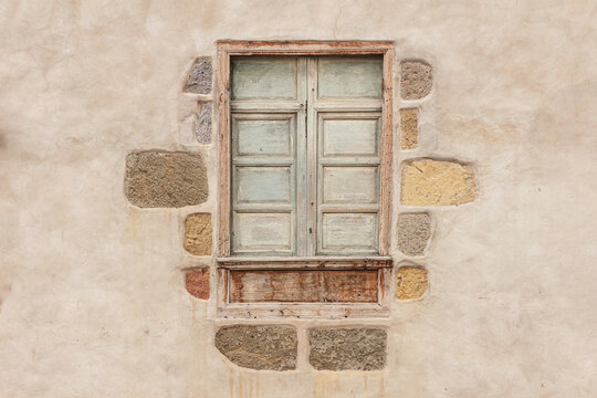 Ventana de madera antigua con marco de piedra y fondo de concreto o cemento de color viejo