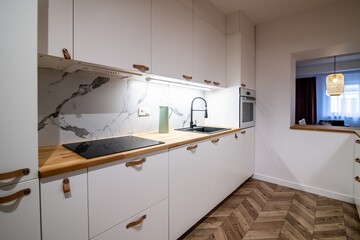 Modern white kitchen in an apartment. Wooden floor