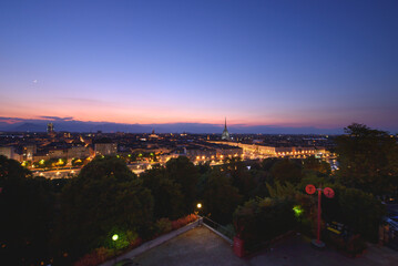 Turin, Italy. Panoramic view of the city illuminated in the evening after sunset. Skyline with the Mole in the evening. July 1, 2022.